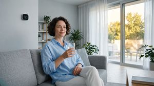 Person staying cool and hydrated indoors during a heatwave with a smart thermostat.