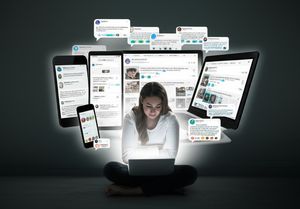 A person feeling isolated despite being surrounded by multiple digital screens and social media feeds.