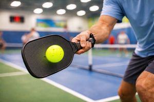 Close-up of a pickleball paddle striking the ball, emphasizing active play and focus.