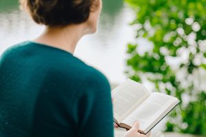 A person sitting quietly in nature, holding a book, contemplating their surroundings, symbolizing early spiritual exploration.