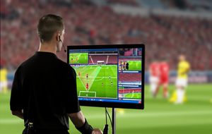 Football referee reviewing an incident on a VAR monitor during a match