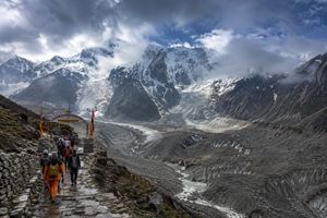 Himalayan pilgrimage path with receding glaciers and distant peaks, signifying evolving travel risks.
