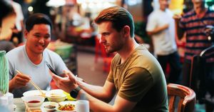 Traveler checking itinerary on phone at a vibrant Hanoi street food stall, disconnected from the joyful locals.